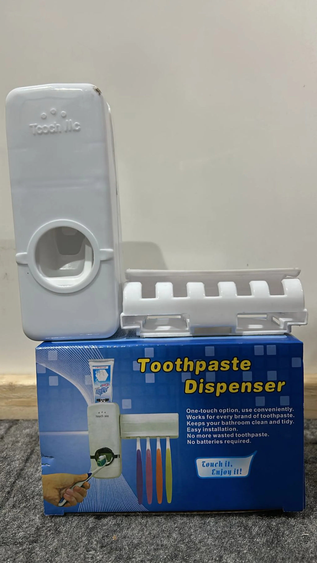 Toothpaste dispenser with packaging on a gray background